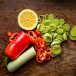 a wooden table topped with sliced vegetables and a lemon