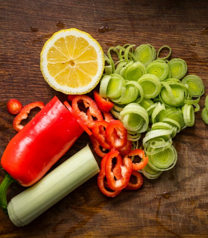 a wooden table topped with sliced vegetables and a lemon