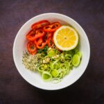 a white bowl filled with vegetables and sliced oranges