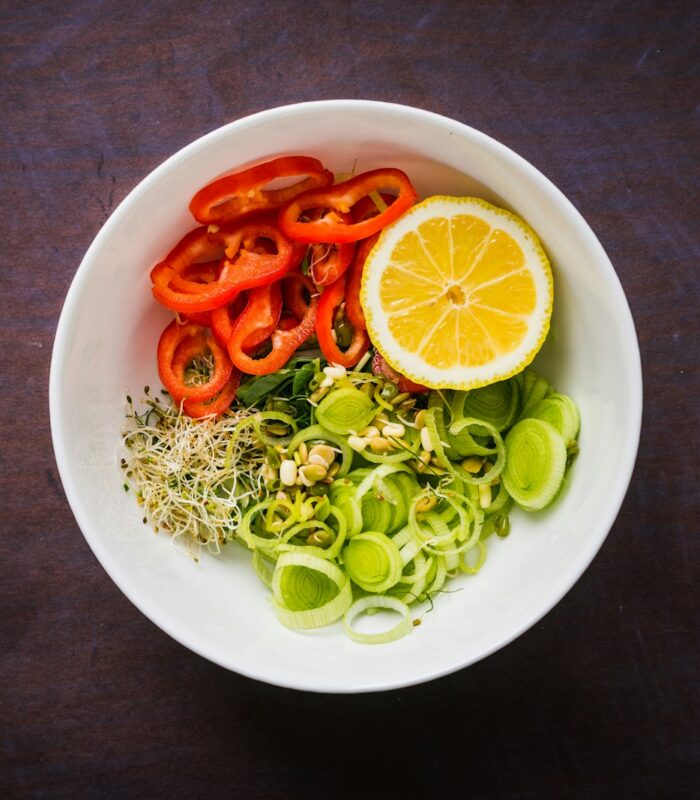 a white bowl filled with vegetables and sliced oranges