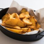 a black pan filled with potatoes on top of a table